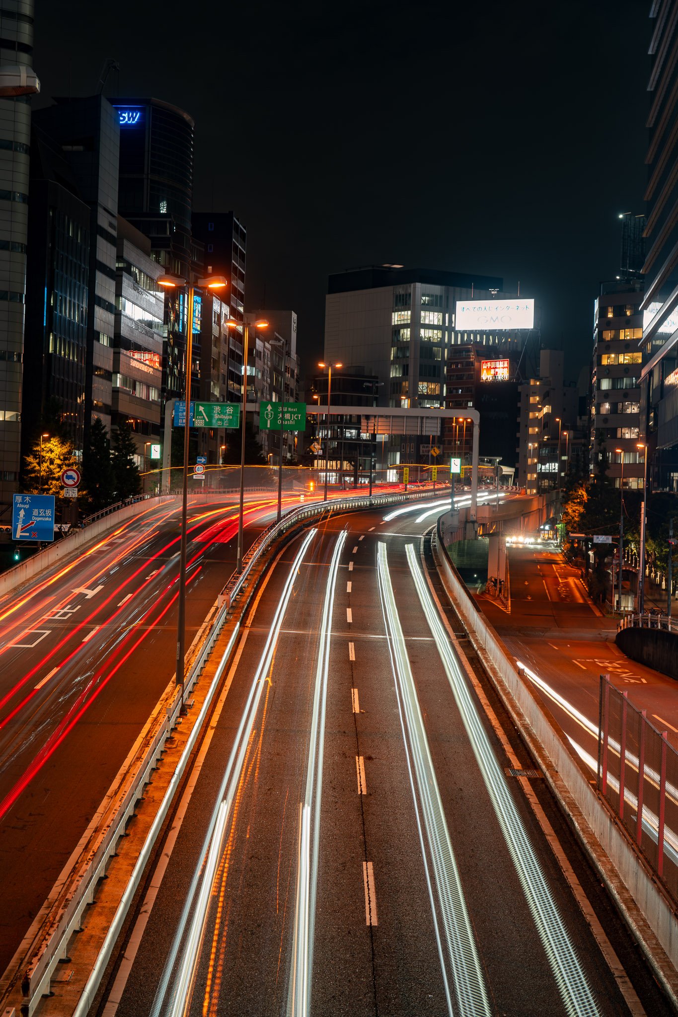 Long exposure night shot of Shibuya highway with vibrant blurred streaks of car lights creating dynamic motion