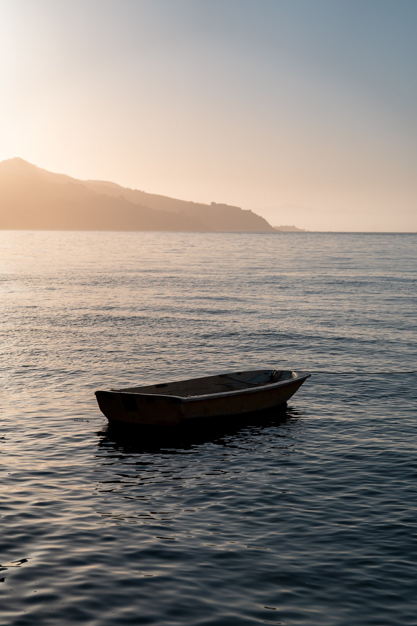 Small boat peacefully floating on calm waters in a scenic bay under clear morning skies