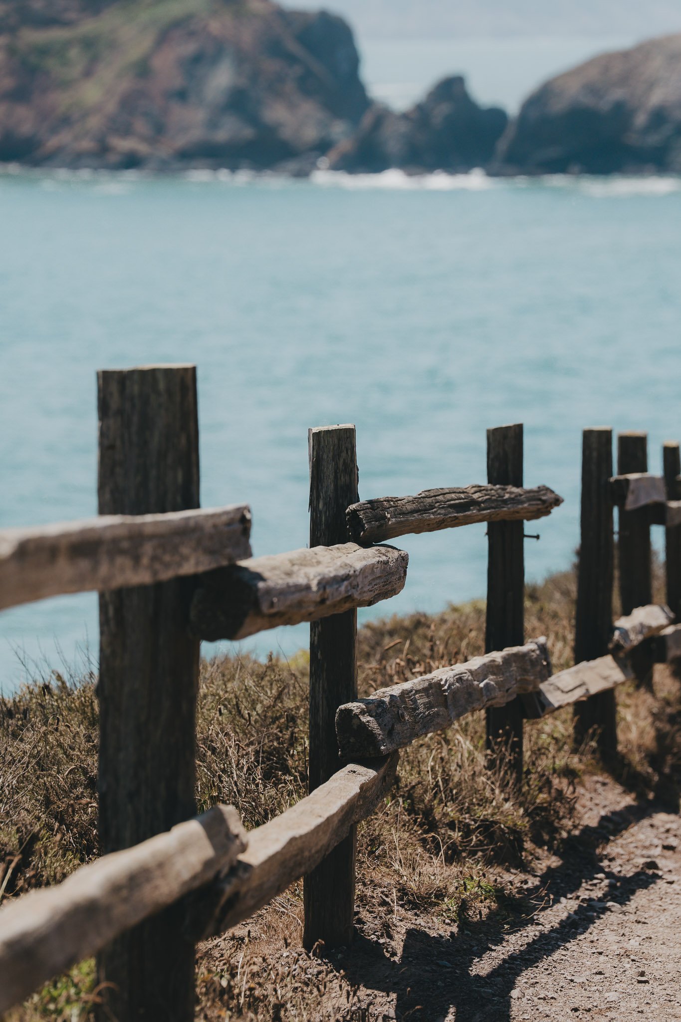 Wooden fence overlooking the vast Pacific Ocean with scenic coastal cliffs and blue skies